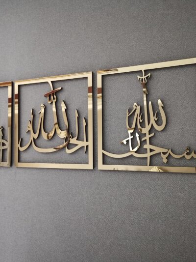 طقم ثلاث لوحات إسلامية ذهبية معلقة على جدار رمادي من زاوية جانبية