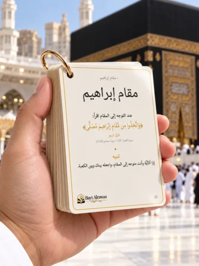 يد تمسك بطاقات دليل العمرة على بطاقة مقام إبراهيم أمام الكعبة المشرفة